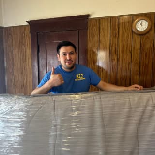 Experienced mover carefully wrapping a mattress in protective plastic cover to ensure safe transport.