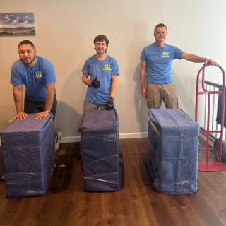 Three experienced movers giving a thumbs-up after carefully wrapping and preparing items for the move.