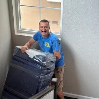 A professional mover taking a wrapped piece of furniture up the stairs, demonstrating experienced handling.