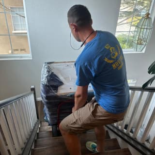 An experienced mover carefully guiding a large item down a staircase, ensuring safe transport.