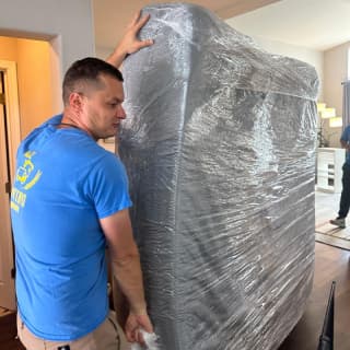 A moving professional positioning a large mattress, demonstrating experience in handling bulky items.