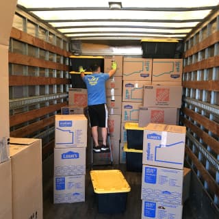 A KZ2 Moving Company employee stacks boxes inside a moving truck, optimizing space for an organized and efficient local or long-distance move.