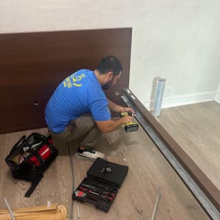 An experienced mover assembling a bed frame with tools, showcasing their professionalism.