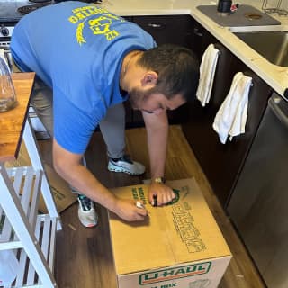 An experienced mover carefully sealing a packed box, preparing it for safe transport.