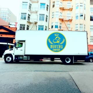 A moving truck with KZ2 Moving Company logo parked in the city, ready to load and transport items.